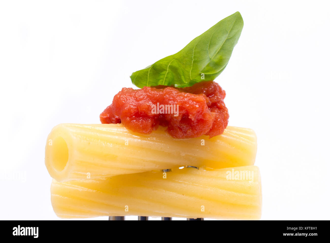 La pasta in bianco sullo sfondo. rigatoni, pomodoro e basilico sulla forcella. cucina italiana concept Foto Stock