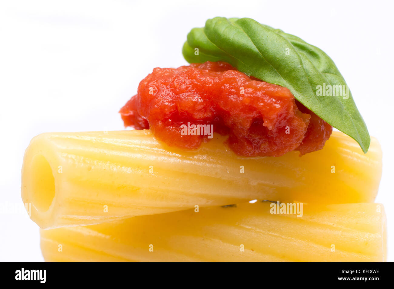 La pasta in bianco sullo sfondo. rigatoni, pomodoro e basilico sulla forcella. cucina italiana concept Foto Stock
