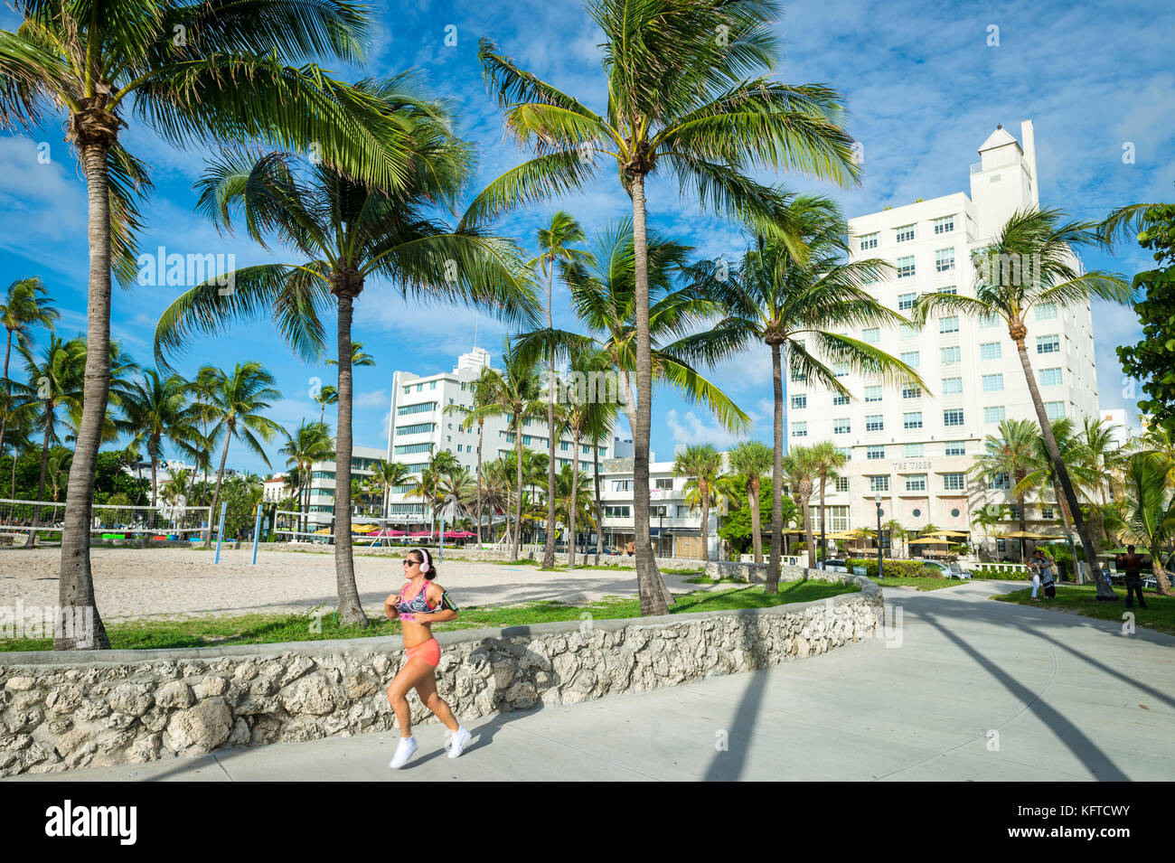 MIAMI - Luglio 23, 2017: atletiche giovane donna fa avanzare lungo la spiaggia di Miami Beach promenade con sfondo iconica edifici art-deco e palme di Ocean Dr Foto Stock