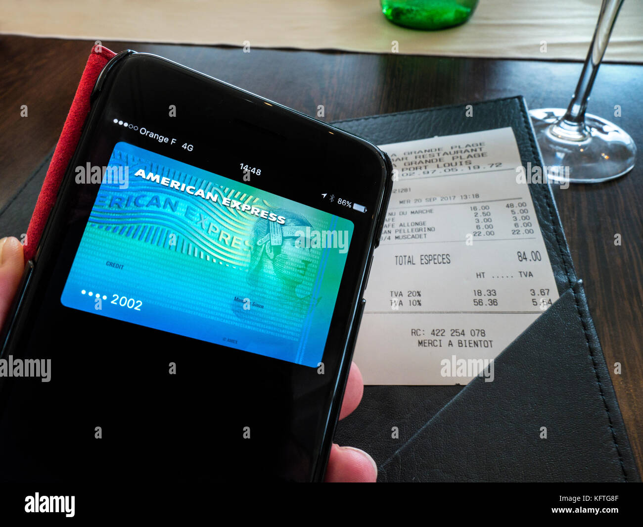 Apple iPhone 7 plus con carta di credito American Express sullo schermo,  pronto per il pagamento fattura utilizzando Apple paga applicazione  software, nel ristorante Francese con moneta euro bill sulla tavola (numero