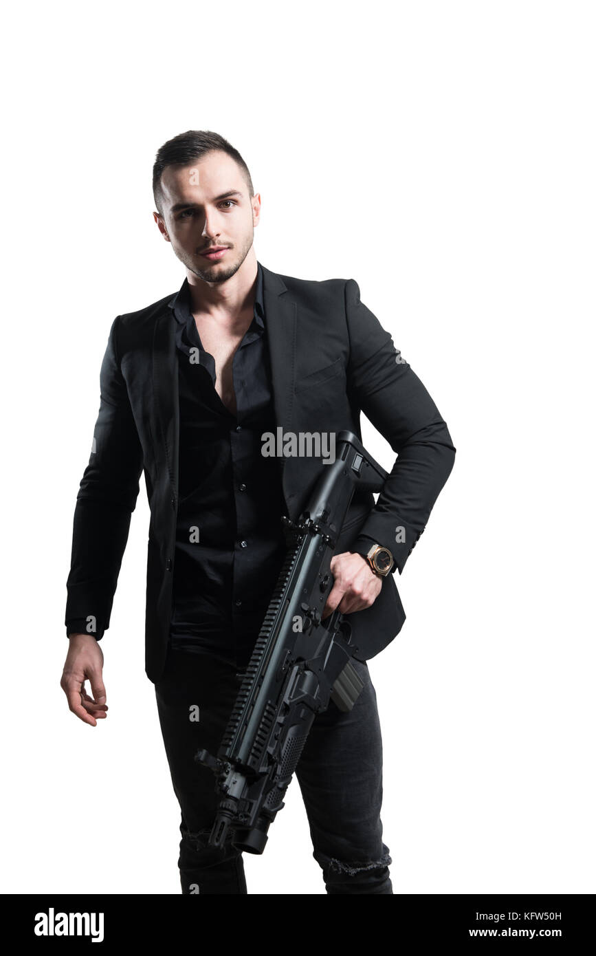 Uomo isolato su uno sfondo bianco con una pistola come egli si trasforma e punta al di fuori della fotocamera Foto Stock