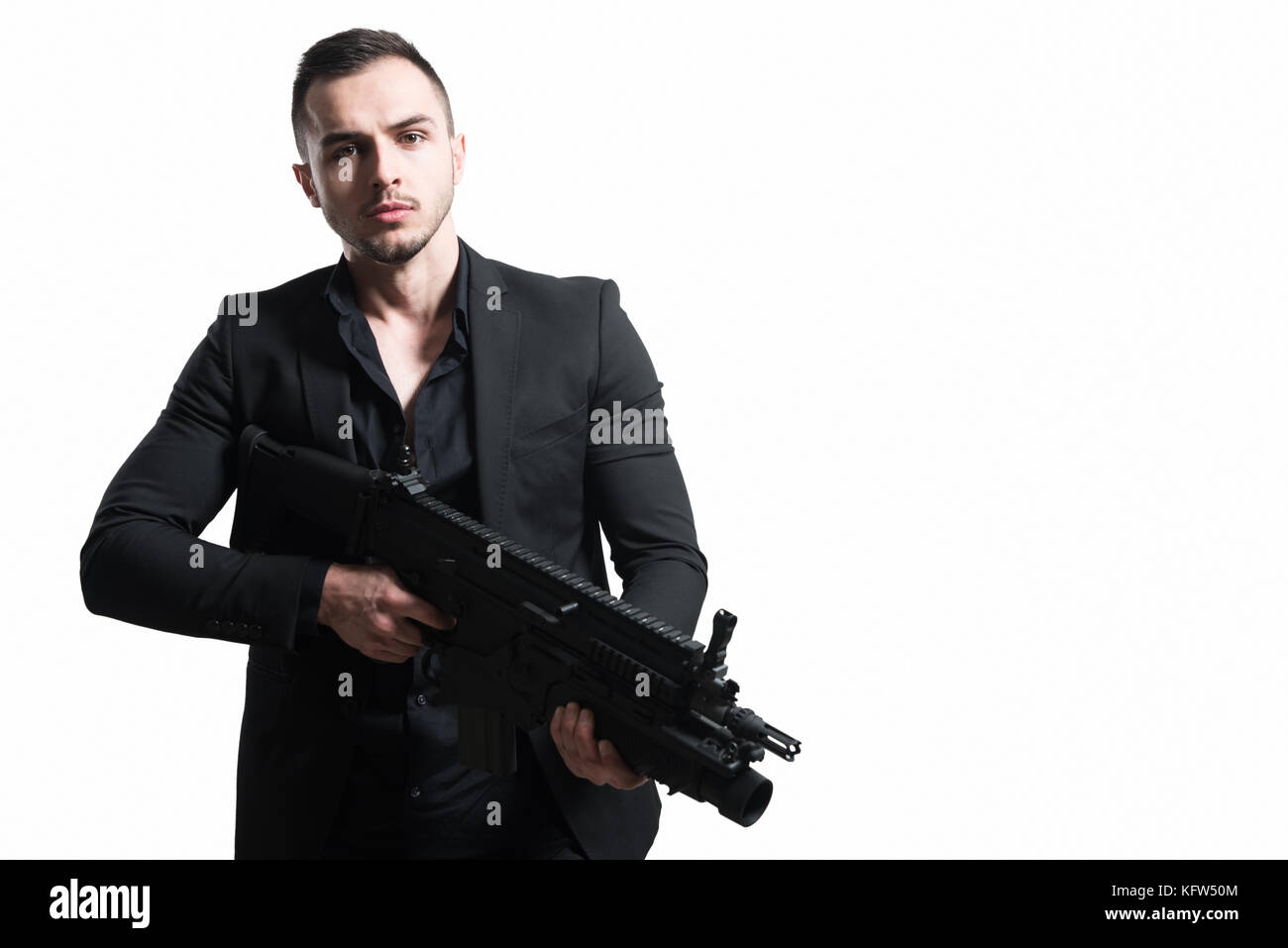 Uomo isolato su uno sfondo bianco con una pistola come egli si trasforma e punta al di fuori della fotocamera Foto Stock