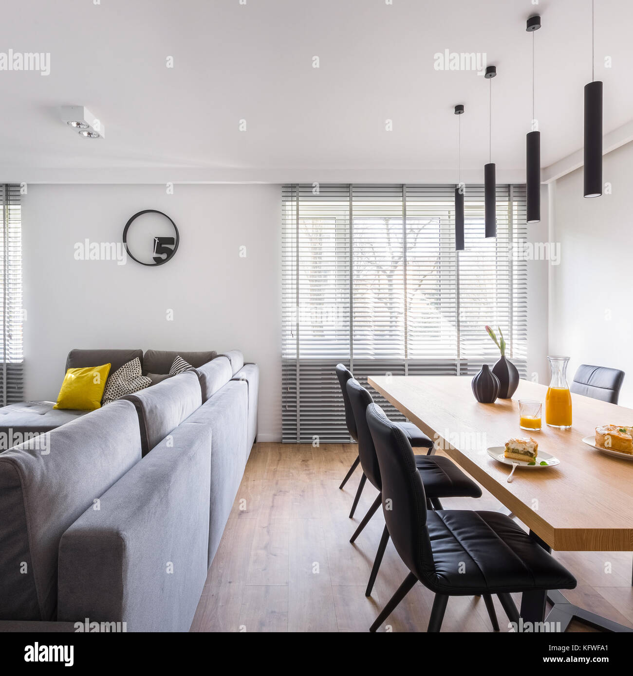 Casa moderna con interni tavolo comunale, sedie nere e grande divano Foto Stock