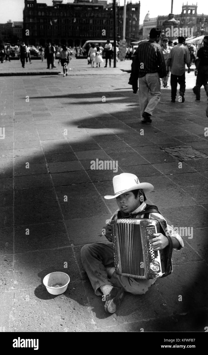 Ragazzo giovane a suonare la fisarmonica e a mendicare per le strade di Città del Messico. Foto Stock