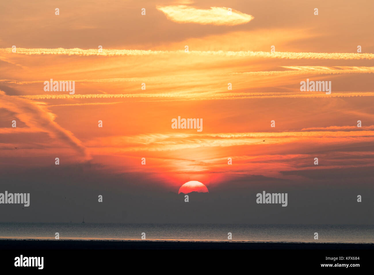 Inghilterra, Ramsgate, Pegwell Bay. Sun salire oltre il canale della Manica e la baia. Orange sky. Foto Stock