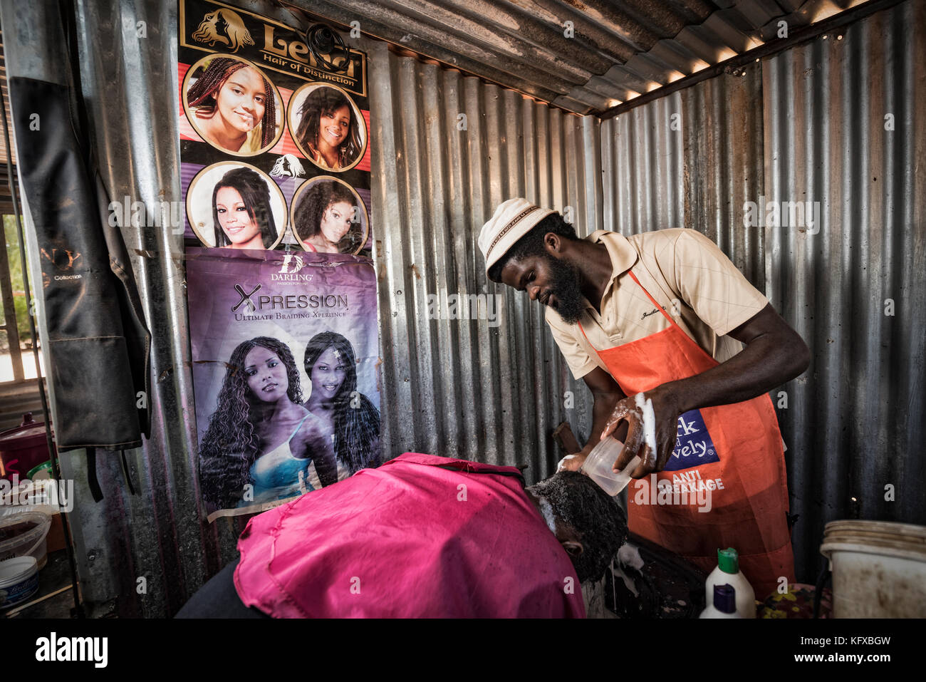 L'uomo africano di lavaggio di un client di capelli shampoo Foto Stock