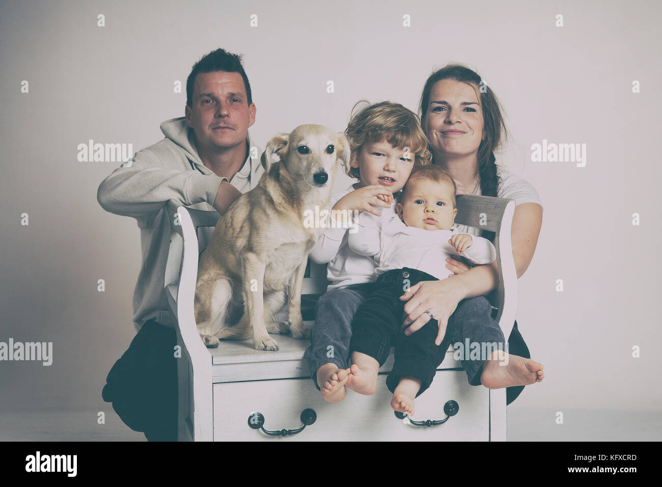 Due generazione famiglia studio ritratto con cane sul grigio e sfondo bianco. Foto Stock
