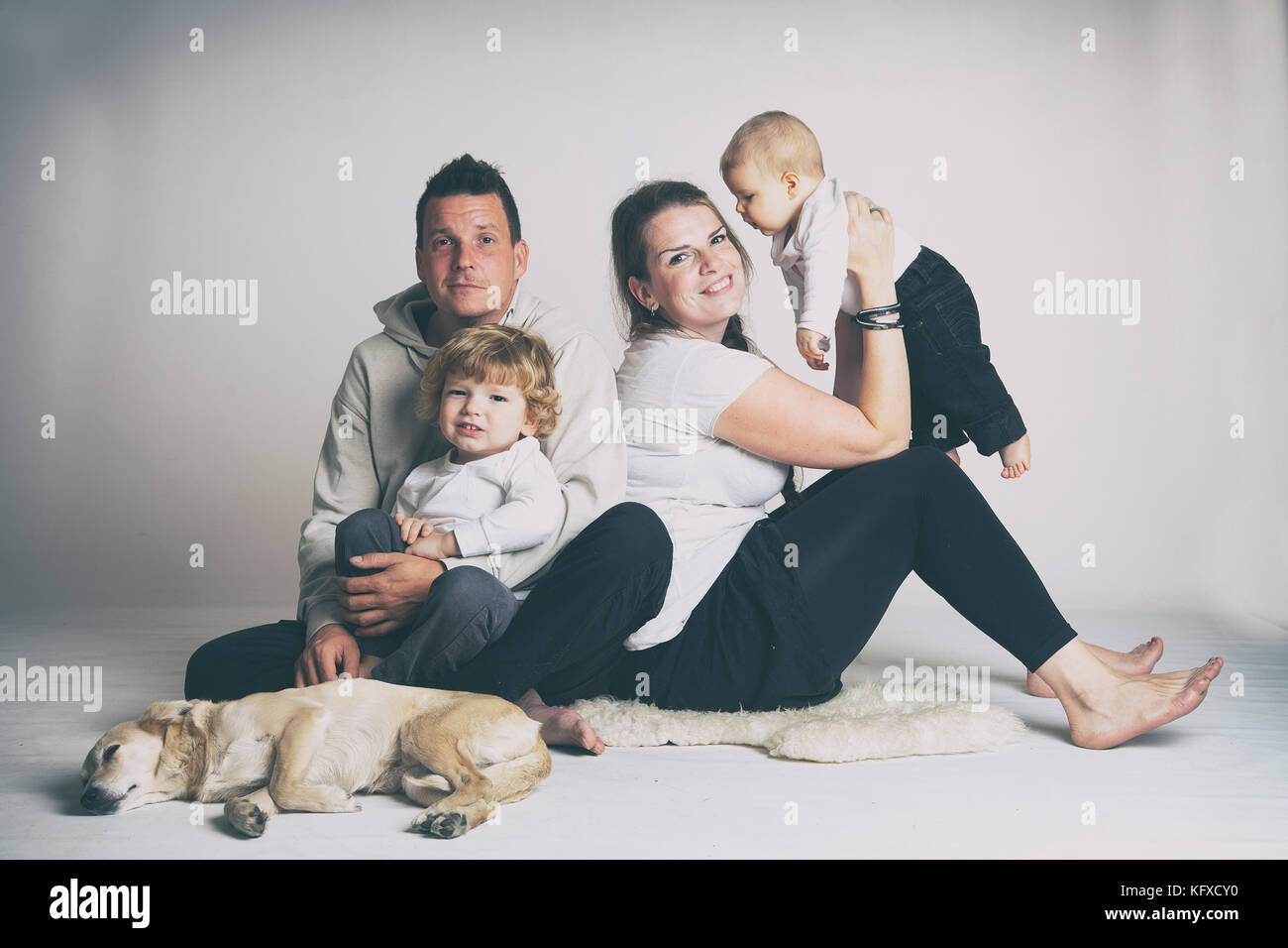 Due generazione famiglia studio ritratto con cane sul grigio e sfondo bianco. Foto Stock