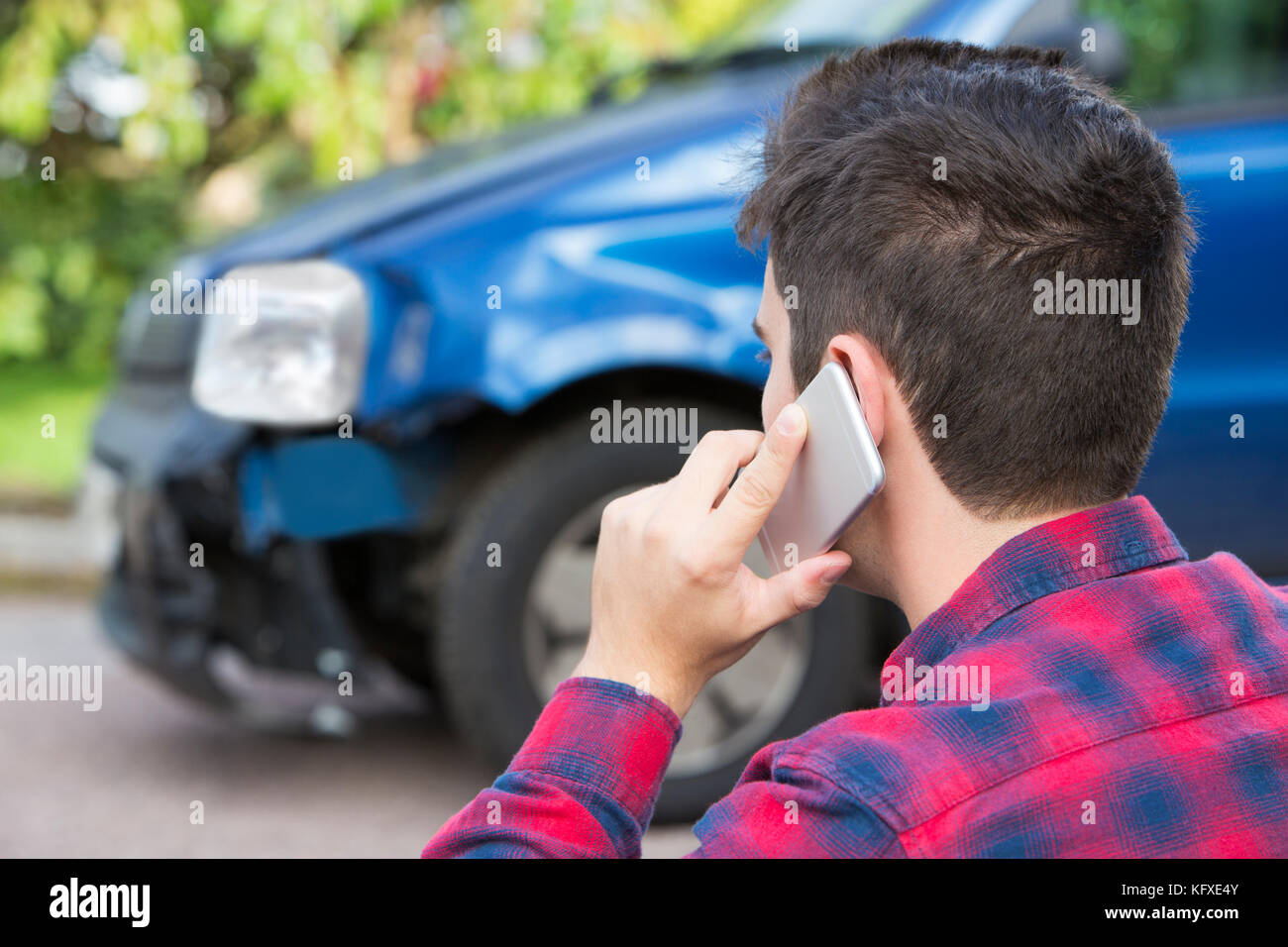 L'uomo reporting car crash sul telefono cellulare Foto Stock