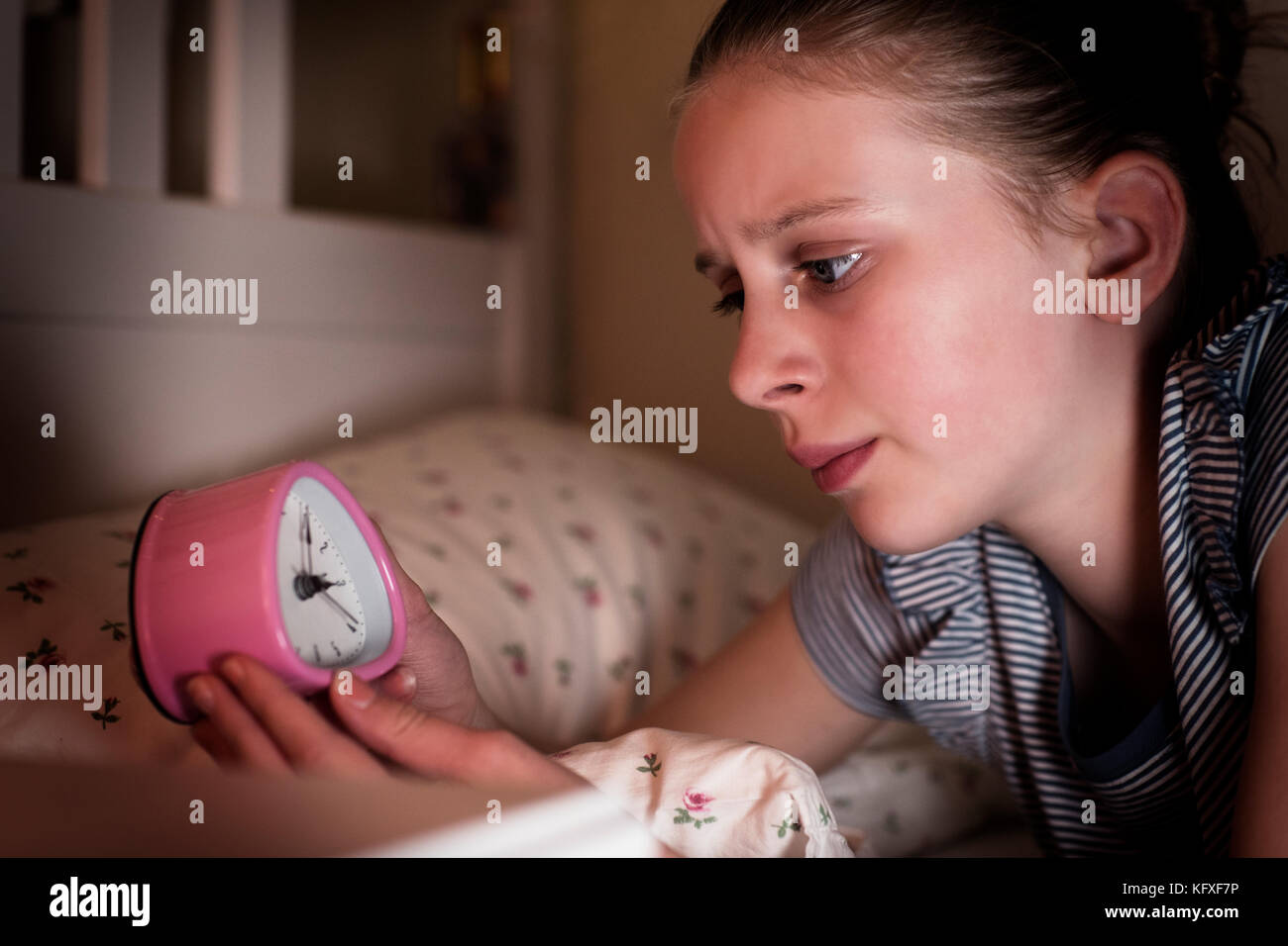 Ansiosi ragazza non riesce a dormire di notte guardando orologio Foto Stock