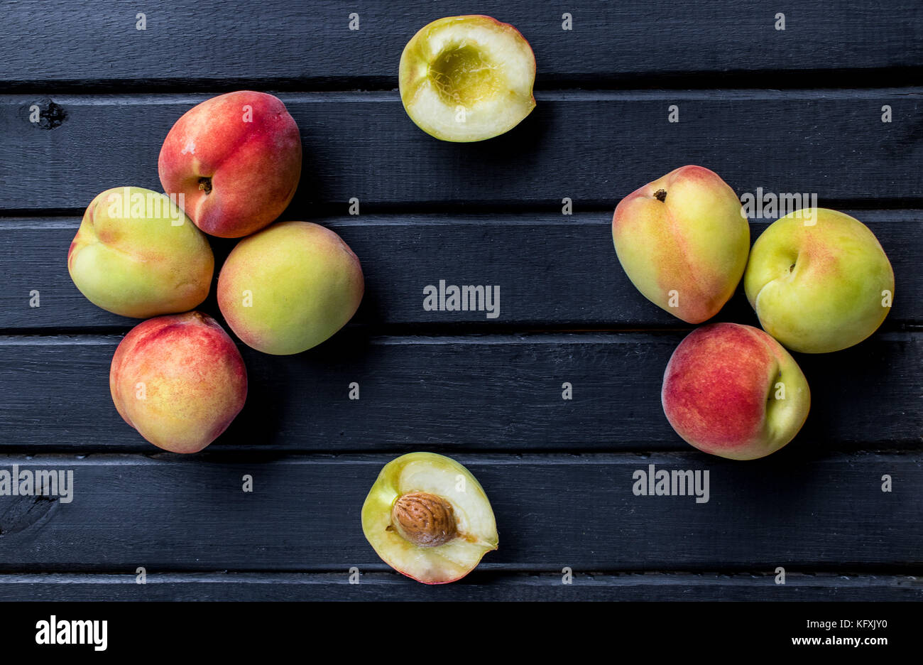 Le pesche intere e tagliate a fette, sulla sommità di un legno giallo superficie di sfondo Foto Stock
