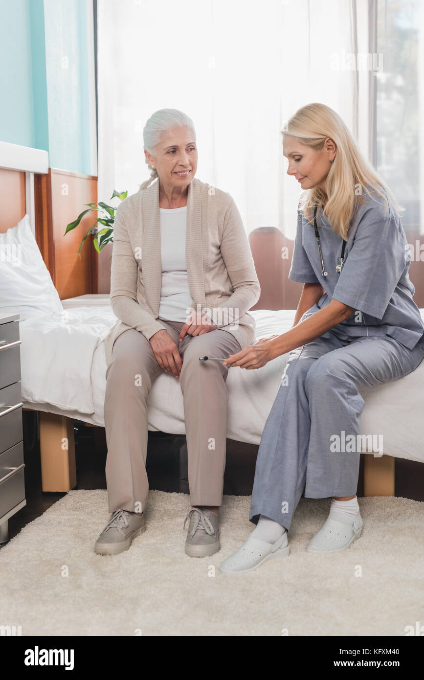 L'infermiera esame paziente con martello reflex Foto Stock