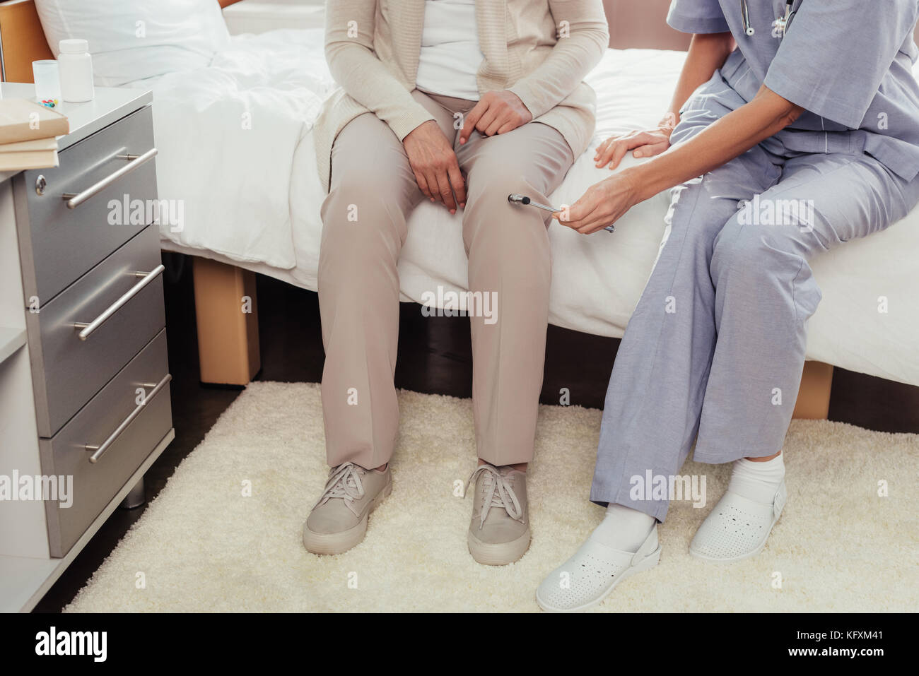 L'infermiera esame paziente con martello reflex Foto Stock