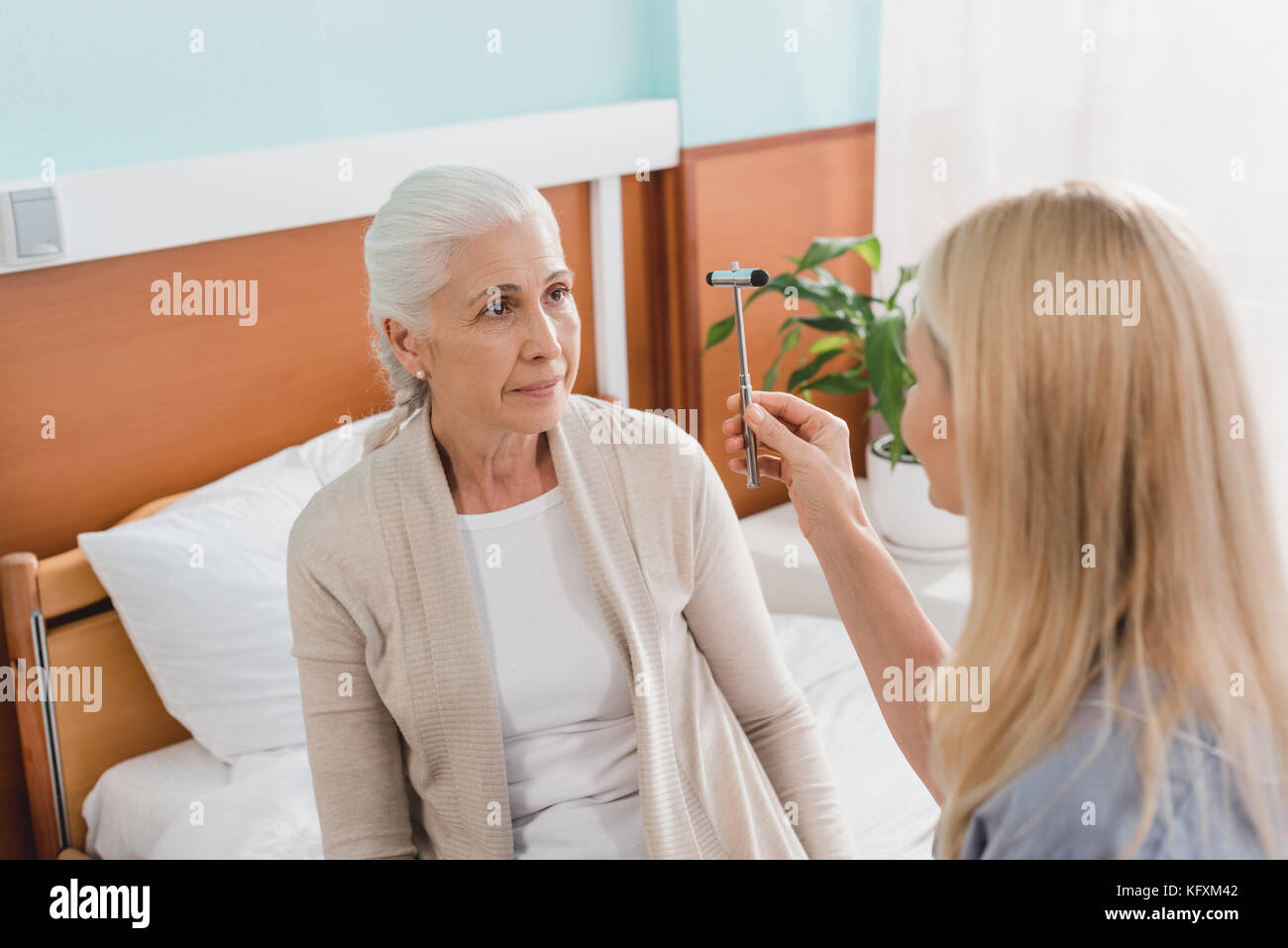 L'infermiera esame paziente con martello reflex Foto Stock