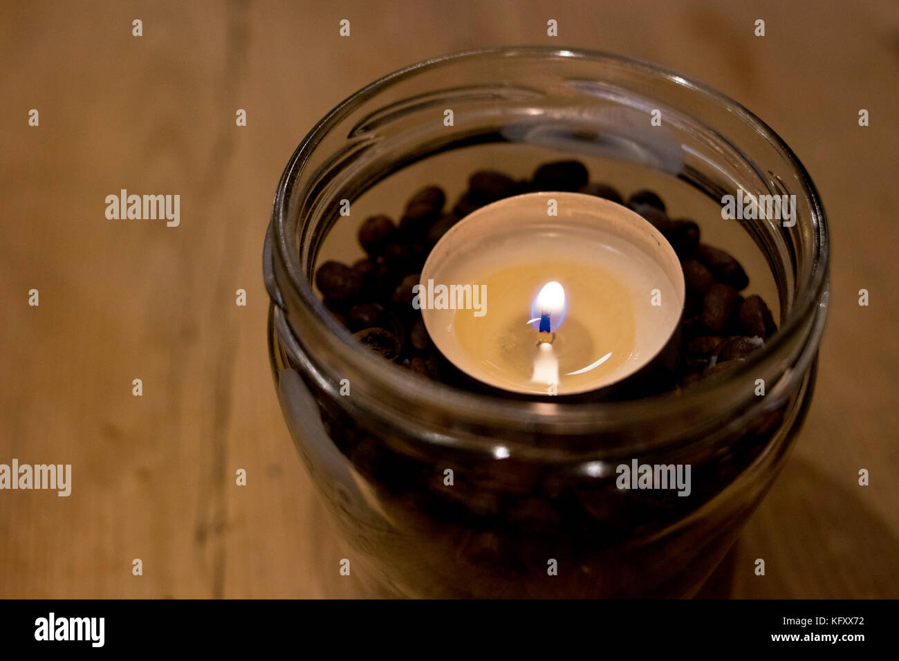 Immagine closeup di una piccola candela all'interno di un recipiente di vetro. Foto Stock