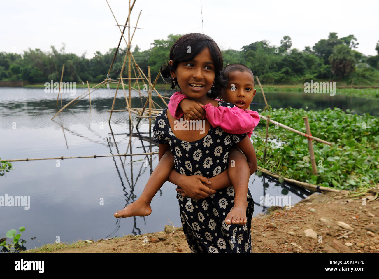 Bristy, 10, tenendo la sua sorella più giovane a Dhaka Foto Stock