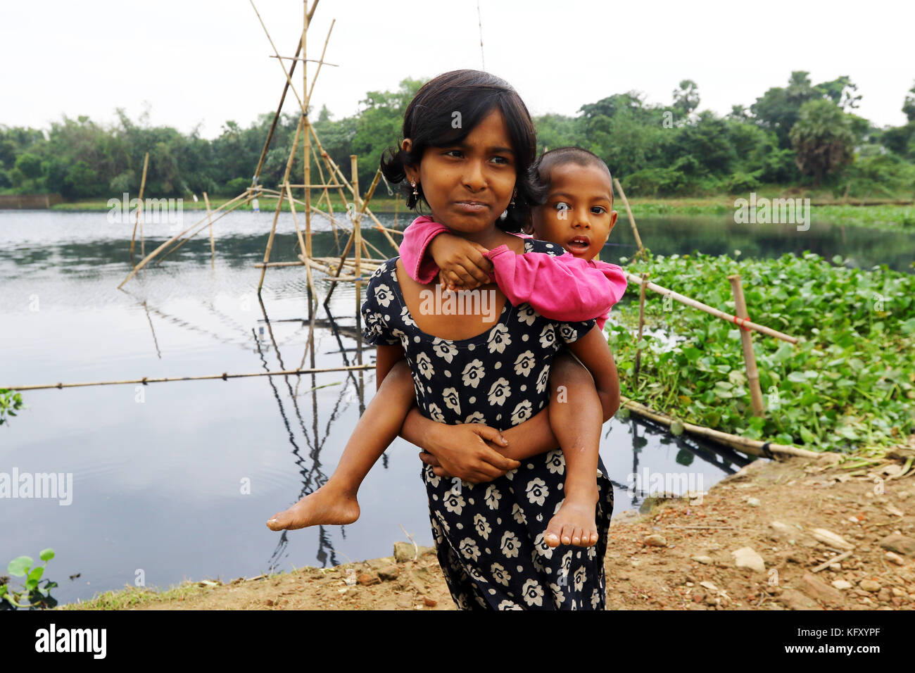 Bristy, 10, tenendo la sua sorella più giovane a Dhaka Foto Stock