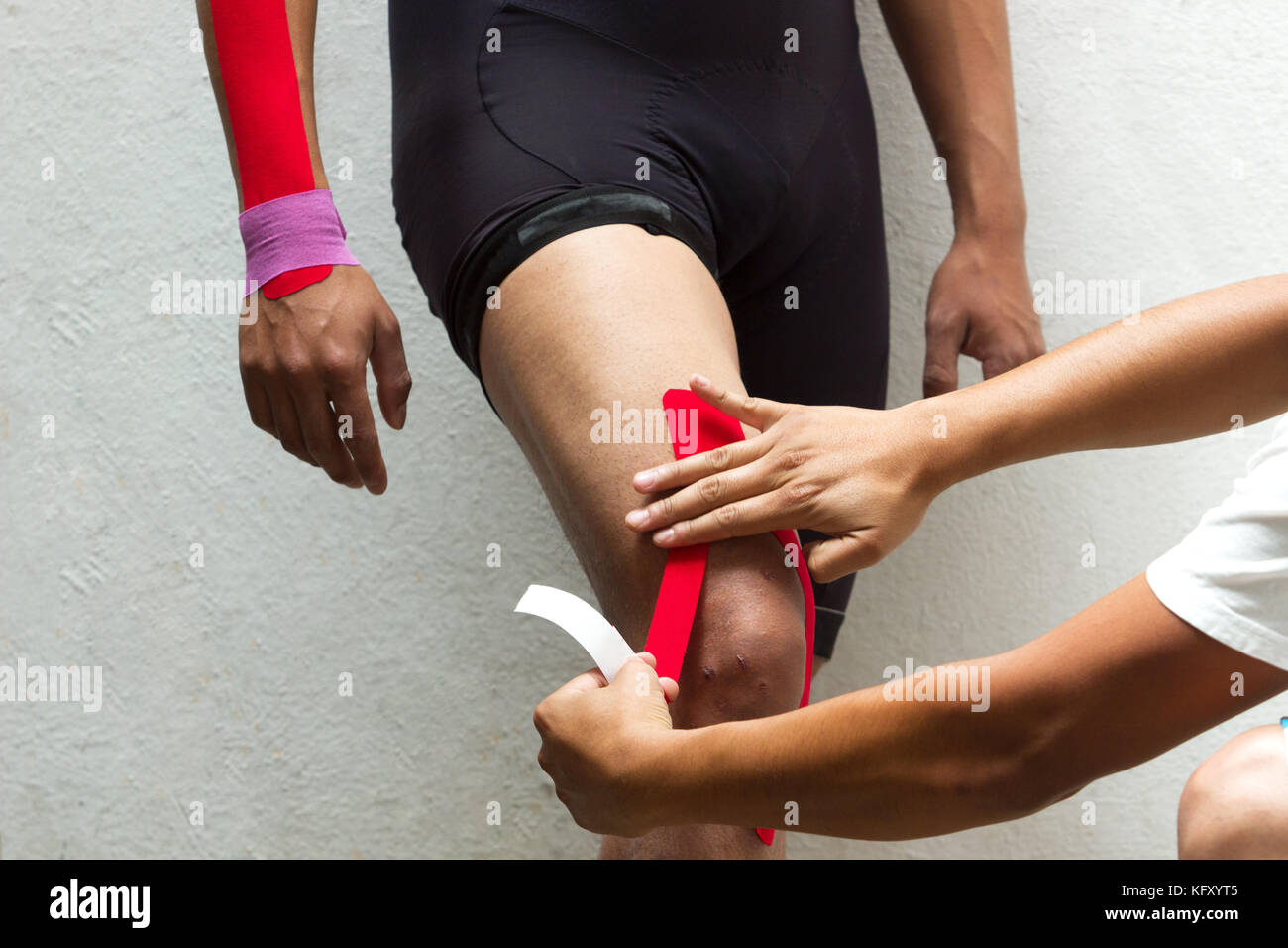 La foto in orizzontale di un medico fisioterapista applicazione kinesio taping sul ginocchio di un ciclista maschio Foto Stock