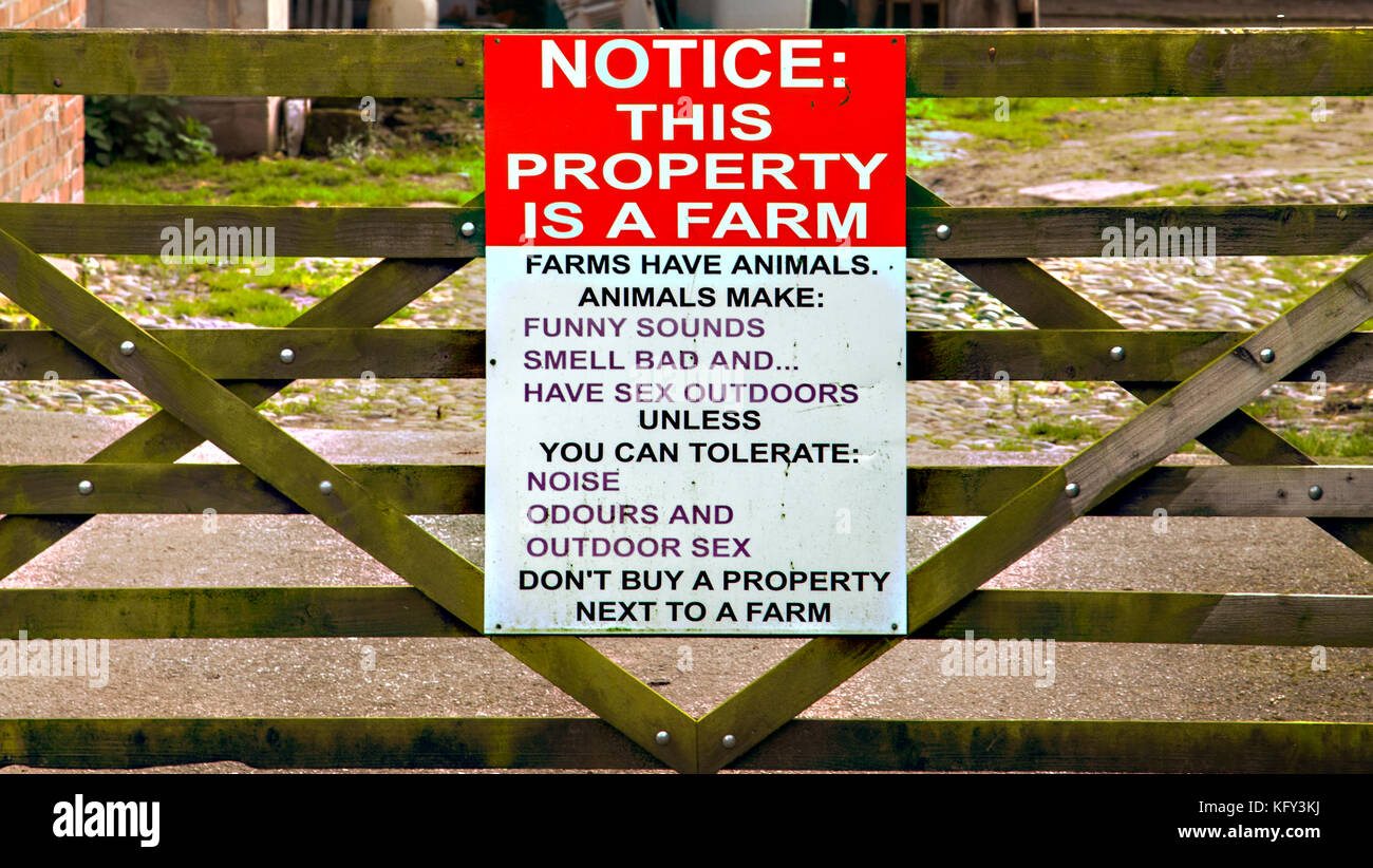 Avviso sul cancello dell'azienda che avverte i vicini che gli animali possono essere rumoroso e puzzolente, quindi non comprate una casa accanto una fattoria se non si può tollerare che Foto Stock