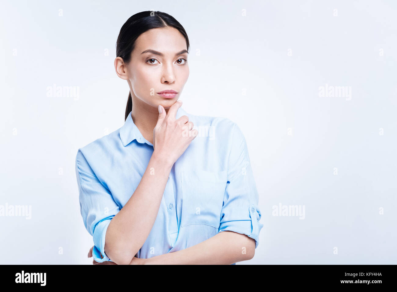 Donna gorgeous in maglietta blu toccando il suo mento Foto Stock