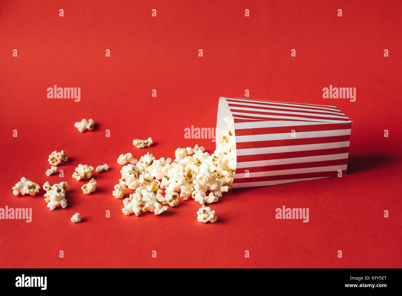 Scatola a strisce con popcorn su sfondo rosso Foto Stock