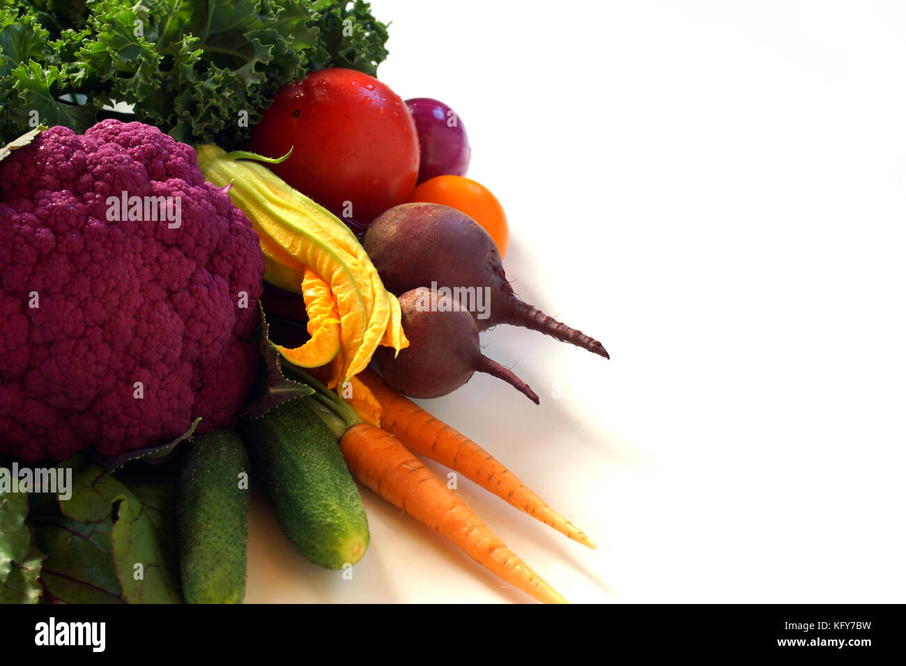 Diversi ortaggi giacciono su una tabella: pomodori, barbabietole, carote, i cetrioli, le cipolle, viola cavolfiore, fiori di zucca, cetrioli fine blu kale arricciata Foto Stock