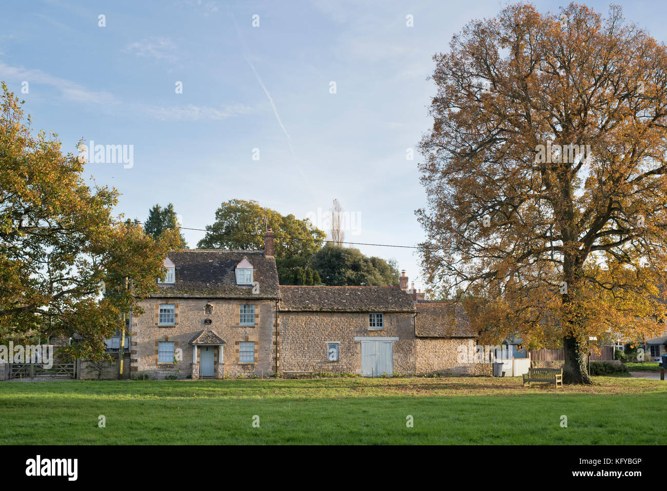 Cottage in pietra e alberi d'autunno nel tardo pomeriggio di sole. Combe, Oxfordshire, Inghilterra Foto Stock