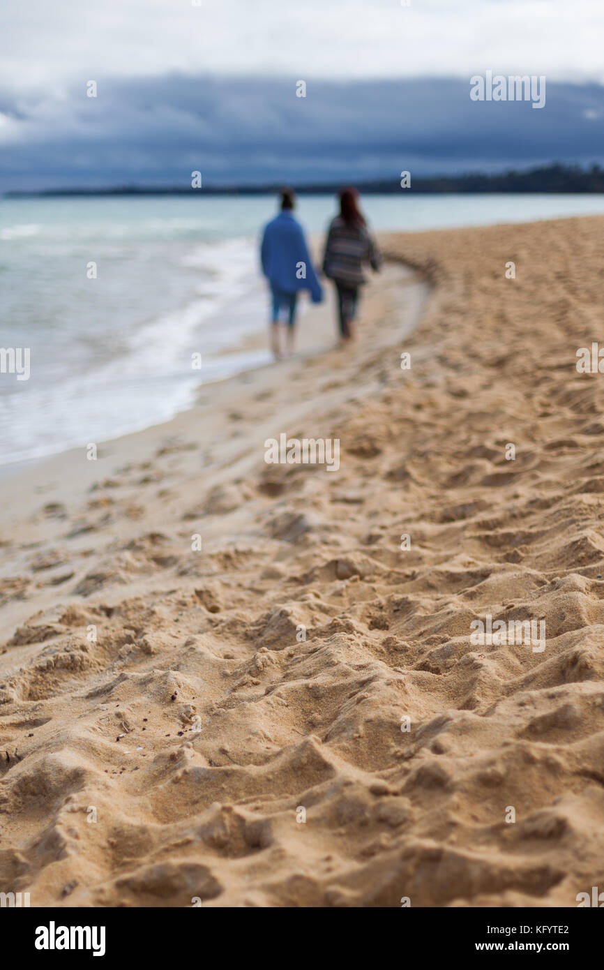 2 Femmine sfocata selettivamente su una spiaggia a piedi Foto Stock