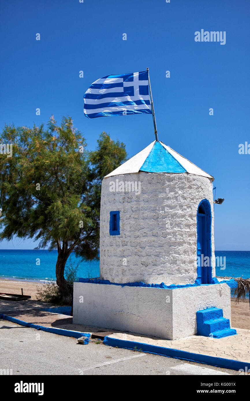 Bandiera Greca battenti sul tetto del mulino a vento ridondante dipinte in nazionale greco di colori blu e bianco alla spiaggia stagna, Archangelos, Rodi, Grecia Foto Stock