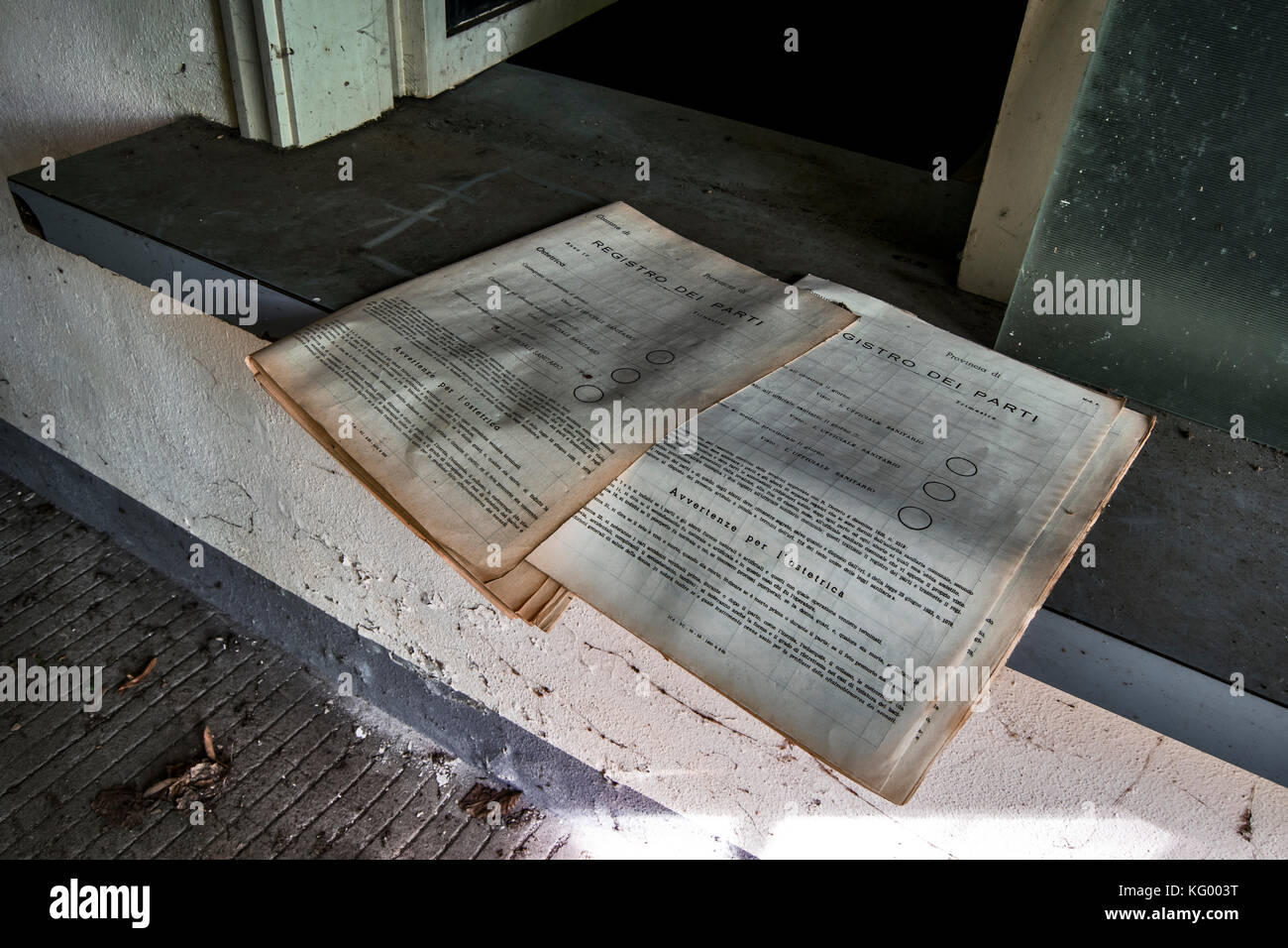 Alcuni vecchi giornali su un davanzale di una finestra all'interno di un manicomio abbandonato Foto Stock