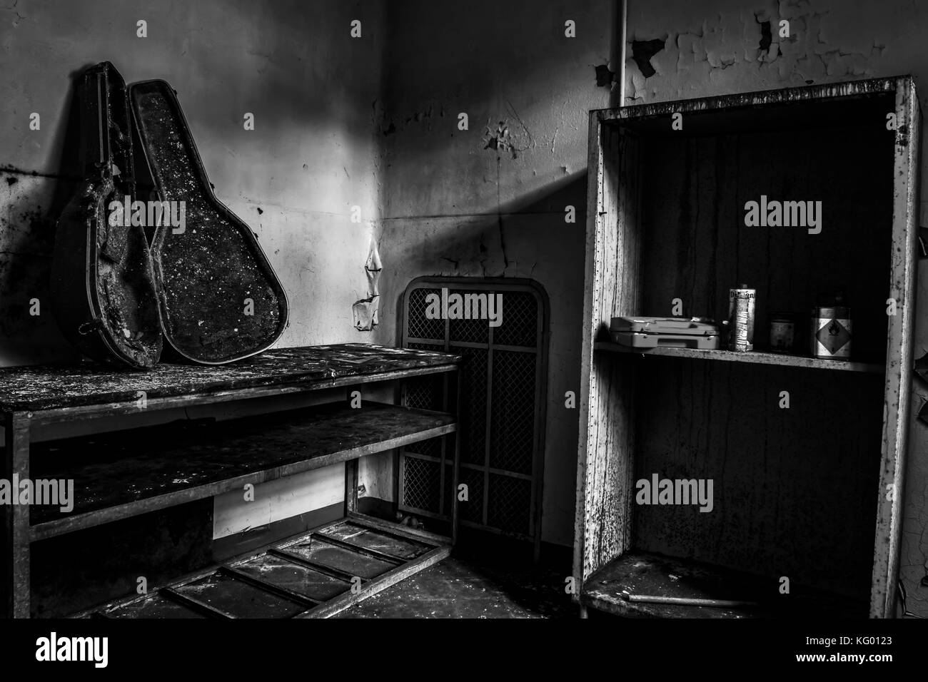 Un caso di chitarra su un tavolo completamente bruciato in una camera di un abbandonato ospedale psichiatrico Foto Stock