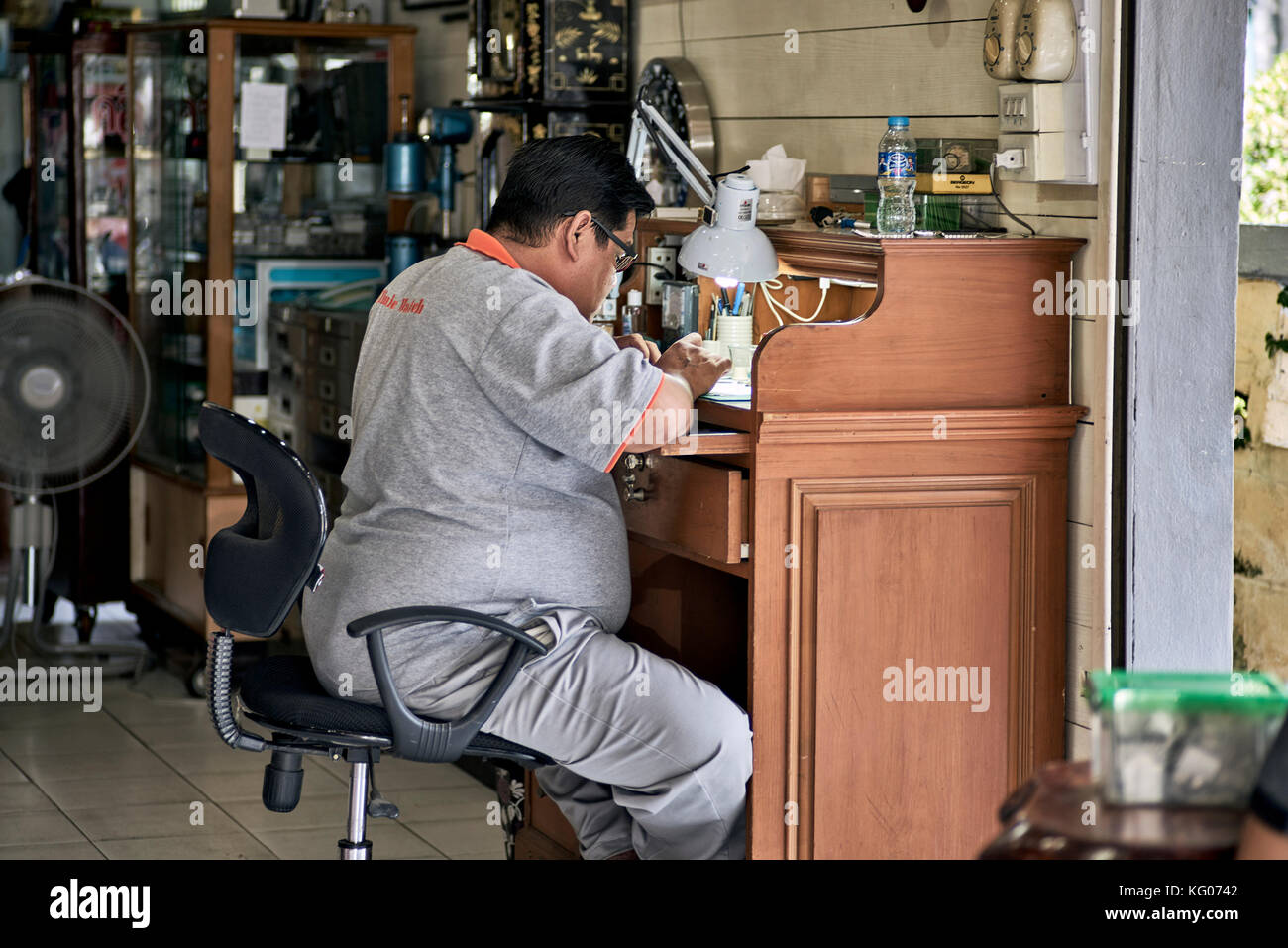 Orologiaio e riparare l'uomo al lavoro nel suo negozio, Thailandia del sud-est asiatico Foto Stock