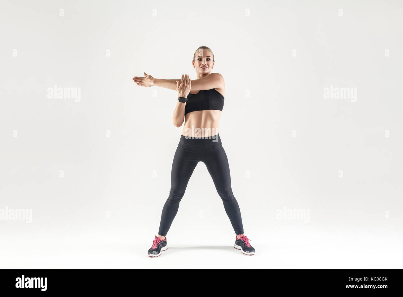 Giovane donna facendo esercizio aerobico e guardando la telecamera. interna shot, sfondo grigio Foto Stock