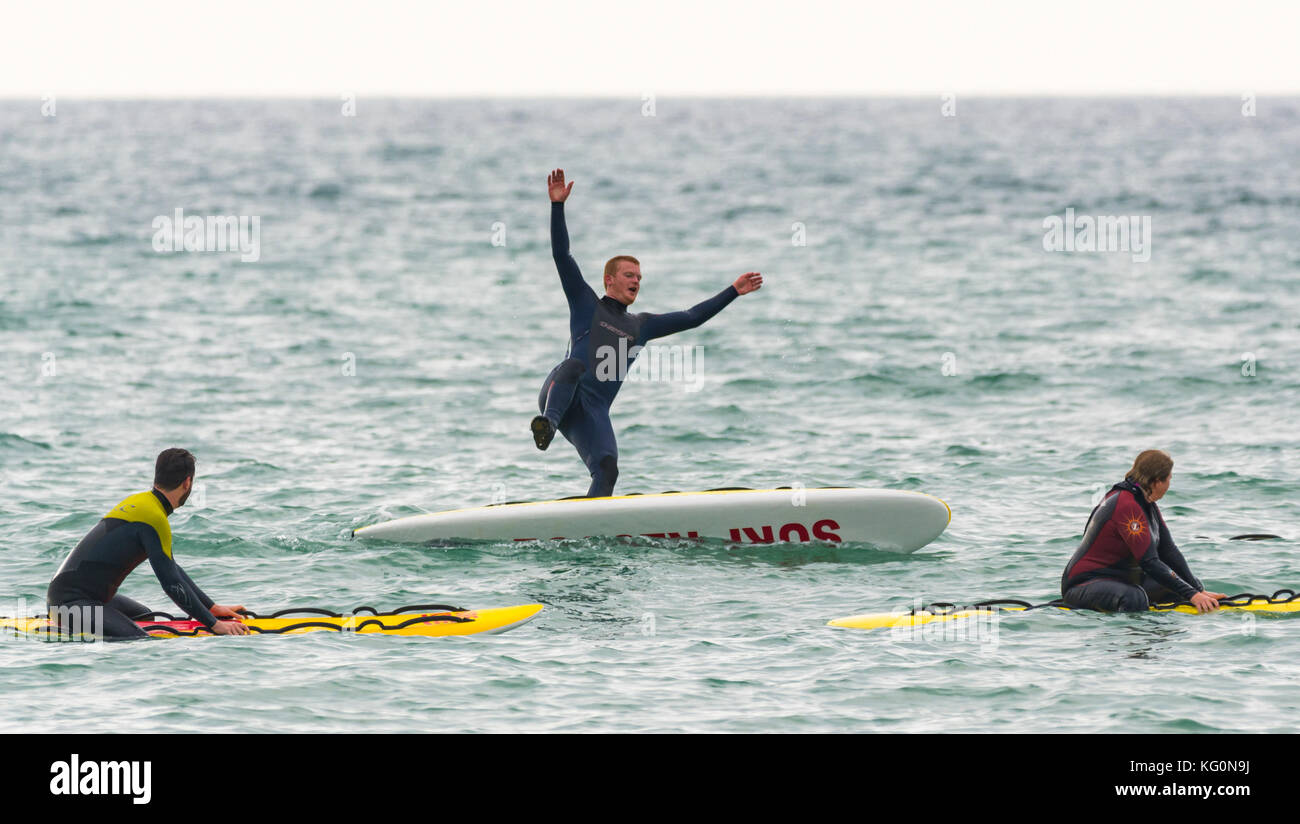 L uomo cade fuori di una scheda a pale in mare. Foto Stock