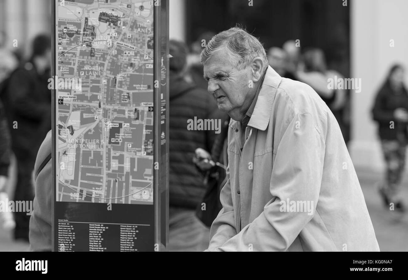 Un anziano che cerca indicazioni su una mappa stradale a Brighton, East Sussex, Inghilterra, Regno Unito. Foto Stock