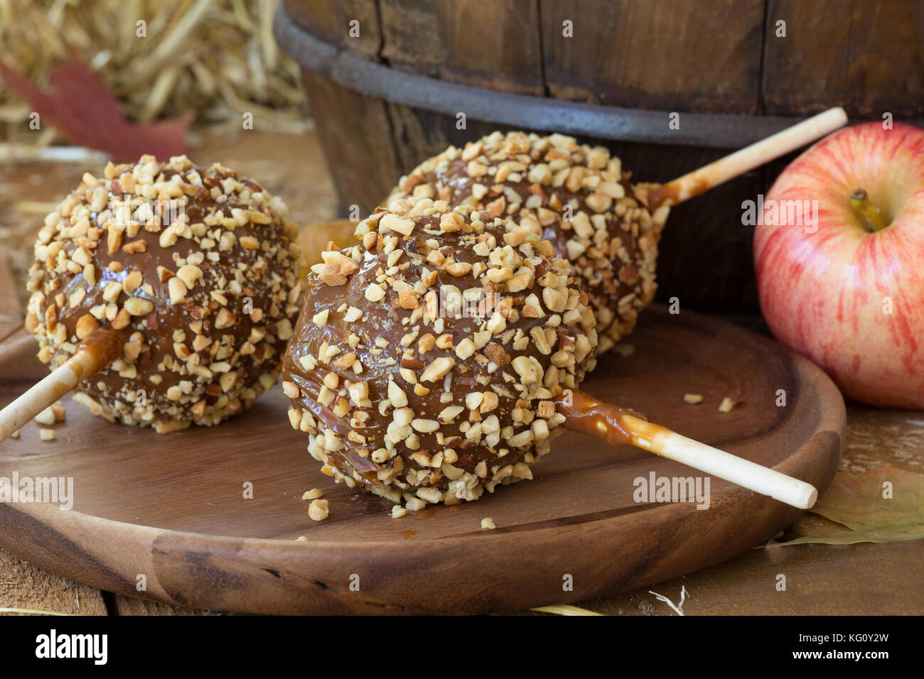 Caramello mele rivestite con dadi su una lastra di legno Foto Stock