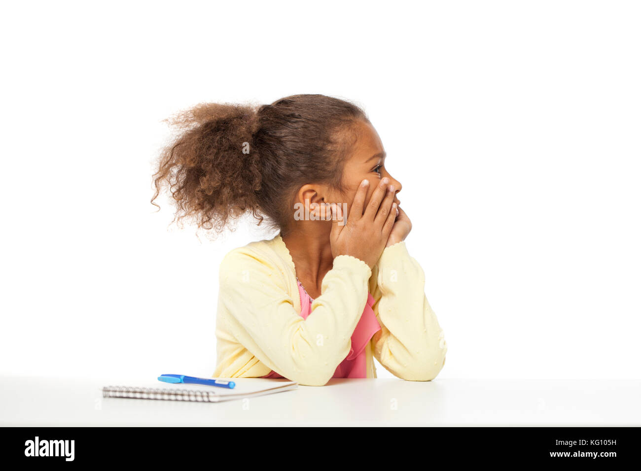 L'istruzione. close up ritratto di African bambina è seduta al tavolo con un notebook per disegno, isolati su sfondo bianco Foto Stock
