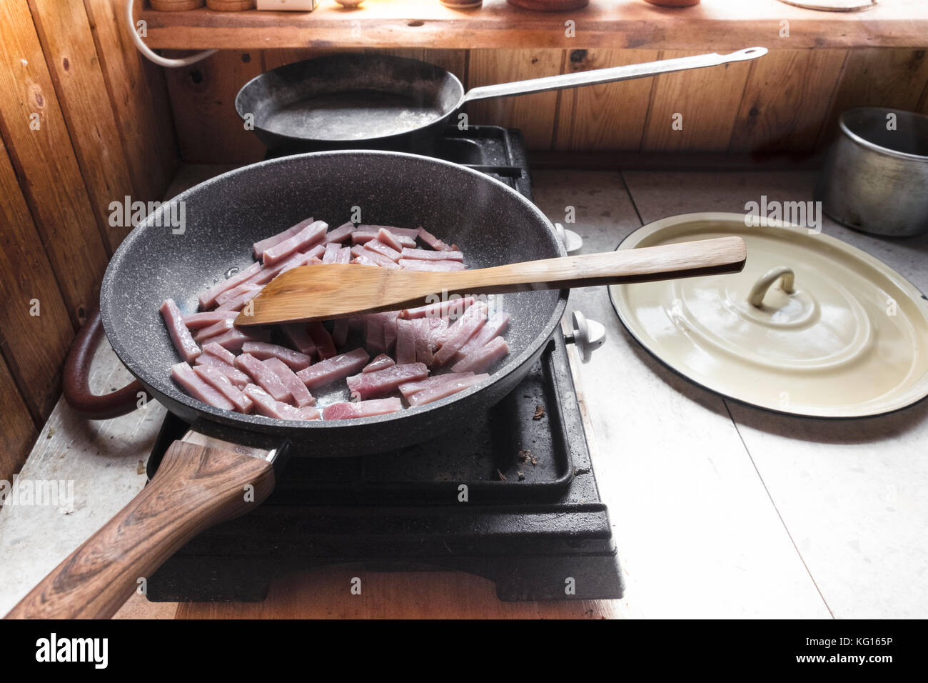 Padella con fette di prosciutto su un fornello a gas top, indoor closeup Foto Stock