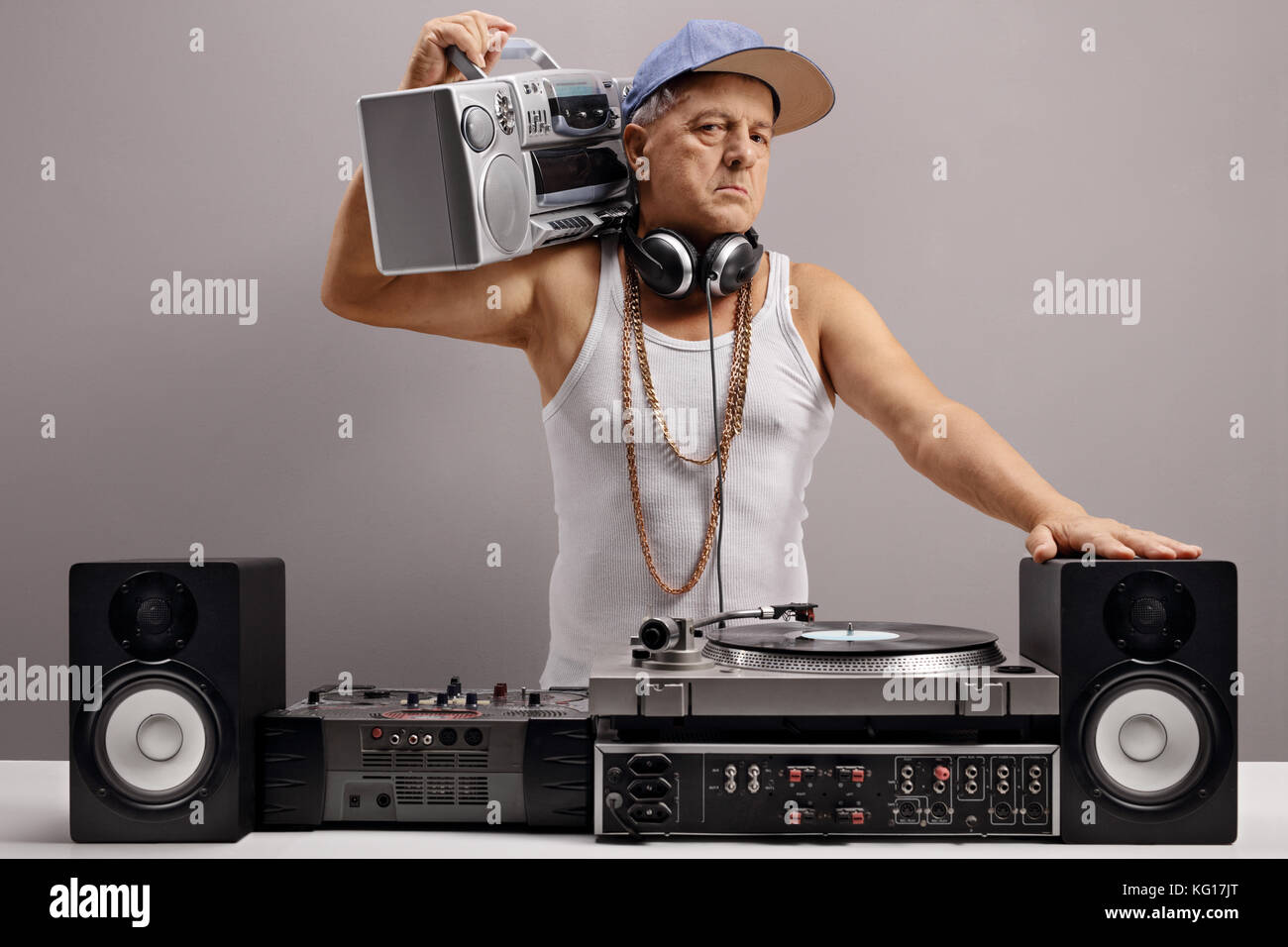 Vecchio dj con un boombox e attrezzature musicali contro un muro grigio Foto Stock