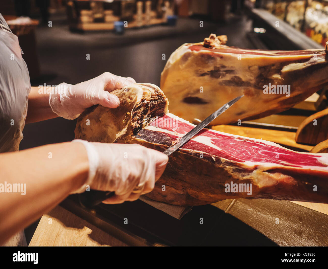 Le mani di una donna in guanti in di mercato o di store tagliare una fetta  di tradizionalmente spagnolo jamon de Bellota. carne vicino Foto stock -  Alamy