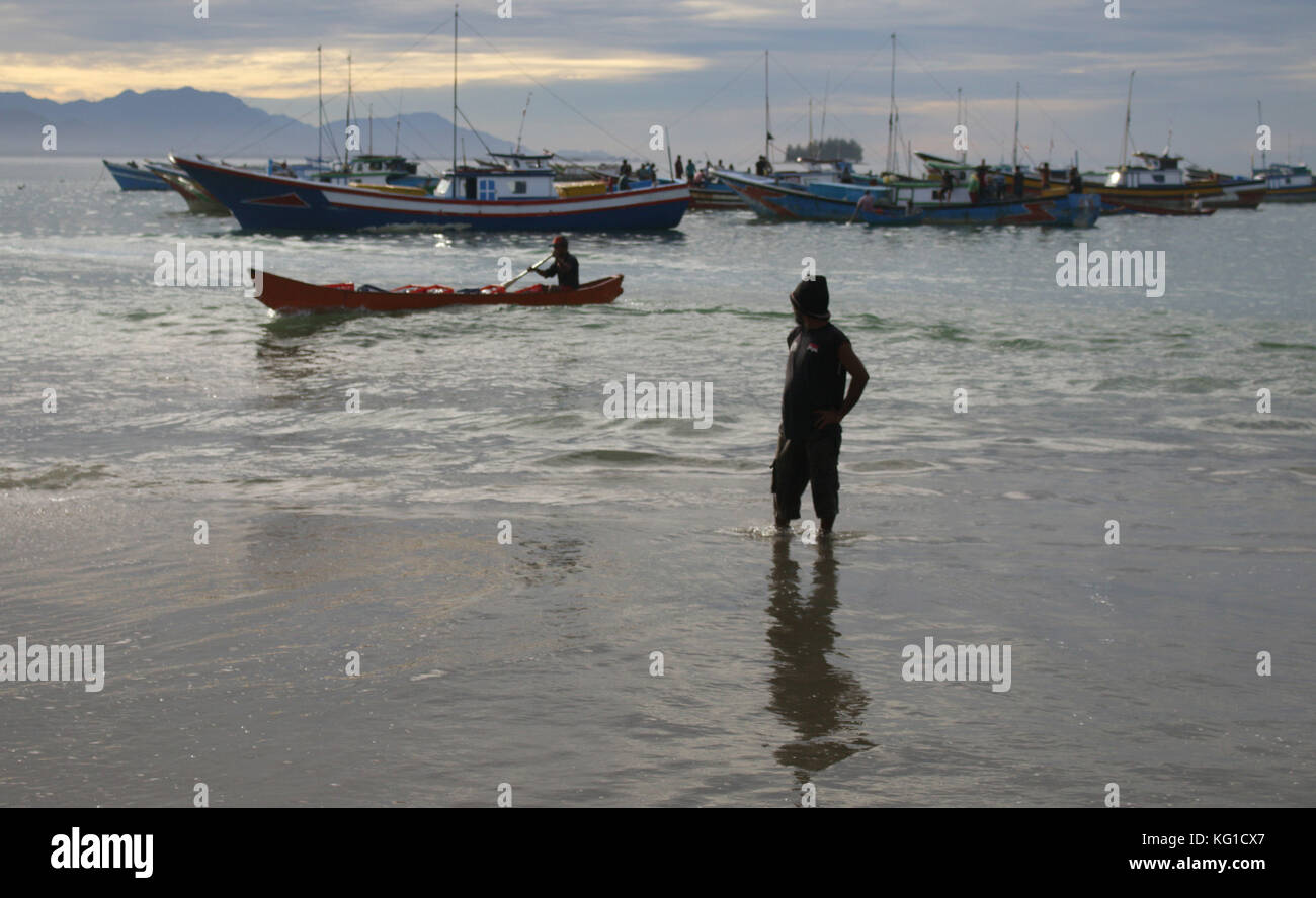 1 novembre 2017 - susoh, Aceh, Indonesia - un pescatore locale visto in piedi in acqua vicino alla riva di fronte a molte barche da pesca..il popolo del sud-ovest della provincia di Aceh sono prevalentemente di pescatori e il reddito regionale nella provincia di Aceh è anche per la maggior parte da oceani. Le attività di pesca di portare a casa la cattura è spesso si trova sulla costa ovest di Aceh..a sud-ovest di Aceh prodotti marini sono abbondanti, ma in crescita del prezzo del pesce nella provincia di Aceh di influenzare il tempo. Se il tempo è brutto quindi il prezzo del pesce anche aumento e viceversa. in aggiunta alle attività dei pescatori e vedute del mare della barca nella uniquen Foto Stock