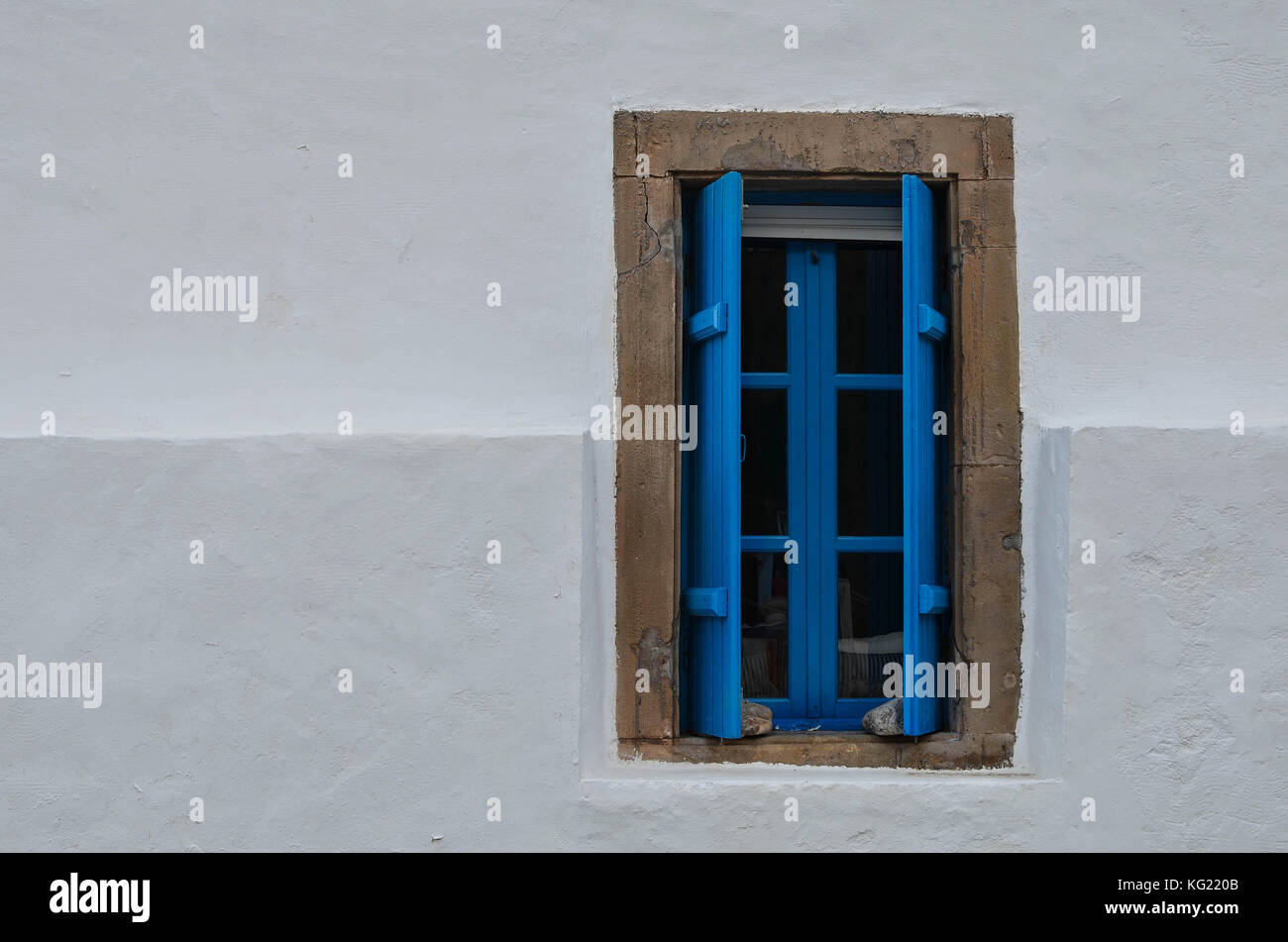 Una finestra blu su una parete bianca. i colori che dominano nelle isole greche. Così semplice ma così bella. Foto Stock
