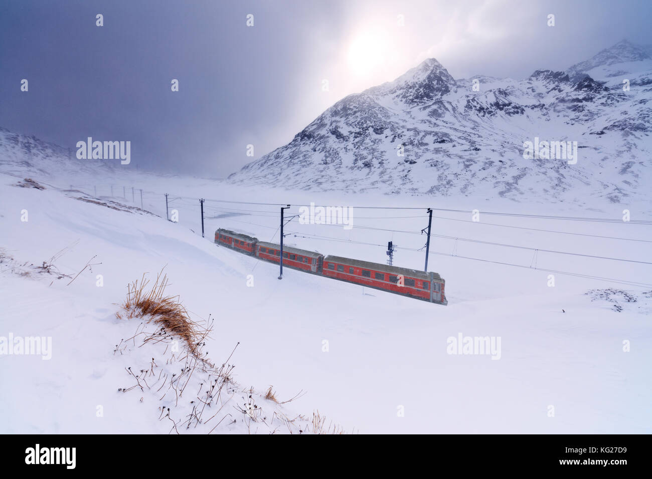 Bernina Express al Passo Bernina sotto una nevicata, Engadina nel cantone dei Grigioni, Svizzera, Europa Foto Stock