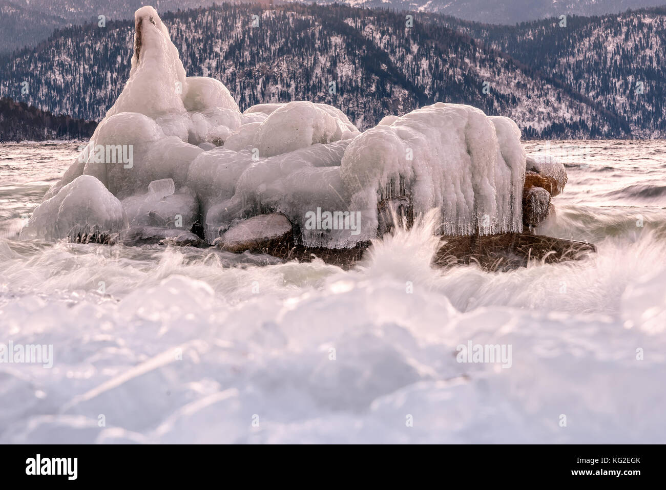 Bella vista invernale con un iceberg nelle acque del lago e del ghiaccio sulla banca sullo sfondo di montagne all'alba Foto Stock