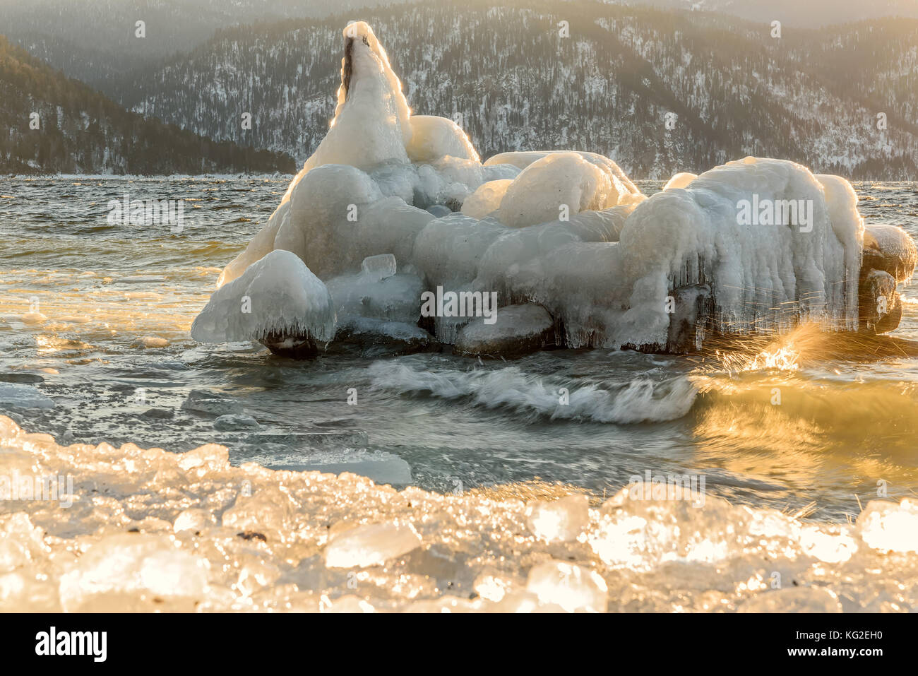 Bella vista invernale con un iceberg nelle acque del lago e del ghiaccio sulla banca sullo sfondo di montagne all'alba Foto Stock