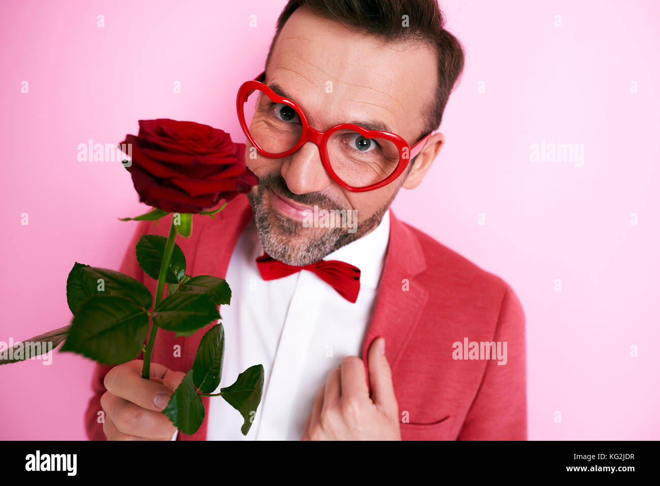 Uomo in tuta rossa tenendo una rosa Foto Stock