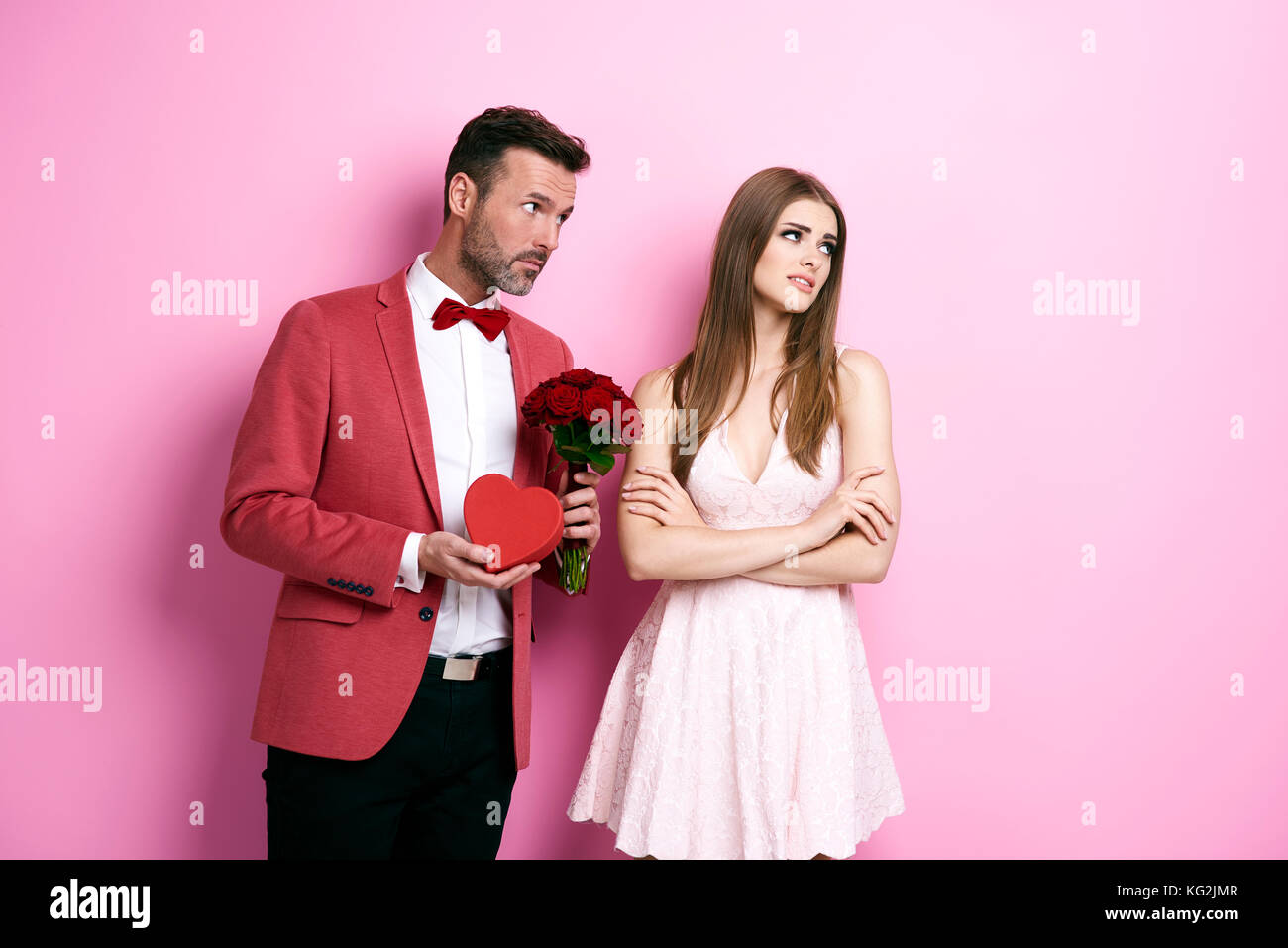 Uomo con mazzo di rosa e scatola di cioccolato che si scusa fidanzata Foto Stock