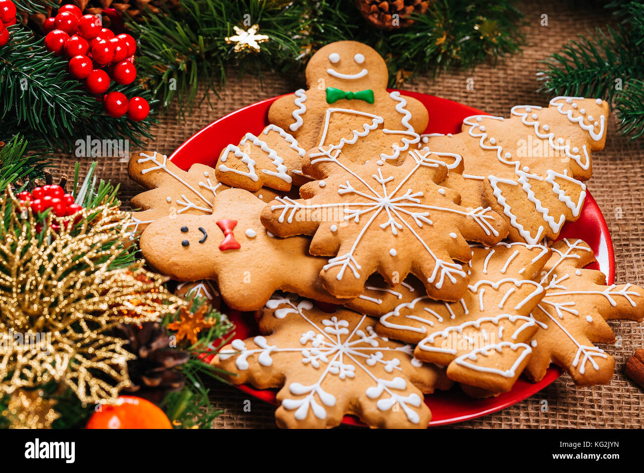 Il natale di panpepato biscotti fatti in casa nel piatto rosso con rami di albero di Natale e Anno nuovo decor e sul tavolo con tovaglia di tela. merry christma Foto Stock