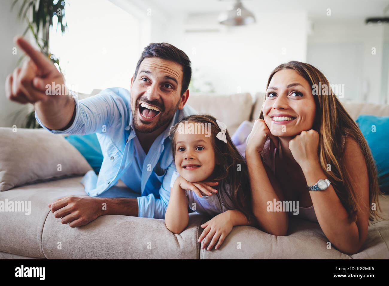 La famiglia felice guardando la televisione a casa loro Foto Stock