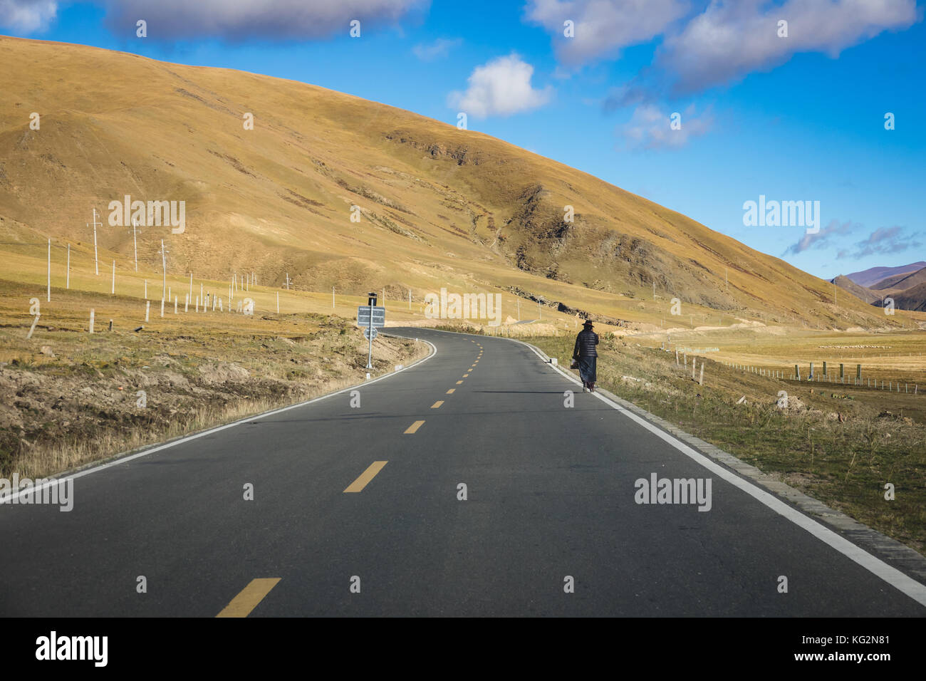 Un uomo che cammina da solo sulla strada di montagna e cielo blu Foto Stock